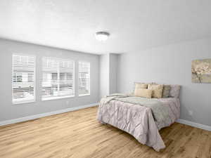 Bedroom with light wood-type flooring and a textured ceiling
