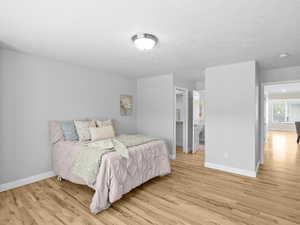 Bedroom with light wood finished floors, connected bathroom, and a textured ceiling