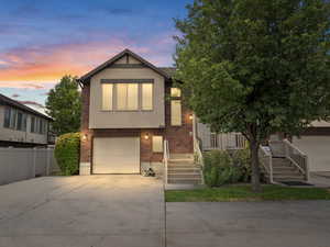 View of front of house featuring brick siding, stucco siding, driveway, and an attached garage