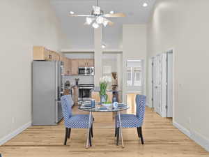 Dining space with high vaulted ceiling, light wood-style flooring, and ceiling fan