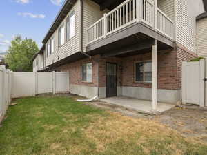 Back of property with a gate, a patio area, a fenced backyard, brick siding, and a balcony