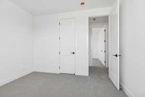 Unfurnished bedroom with light carpet and baseboards