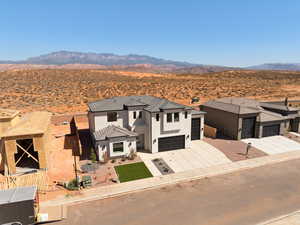 View of front of home featuring driveway, stucco siding, a mountain view, and a garage
