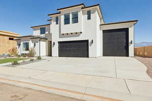 View of front of home with stucco siding, concrete driveway, and a garage