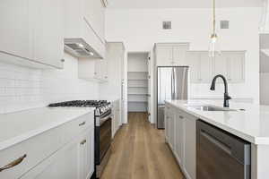 Kitchen with backsplash, appliances with stainless steel finishes, dark wood-style flooring, and white cabinetry