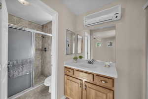 Full bath with a wall unit AC, a stall shower, vanity, and light tile patterned floors
