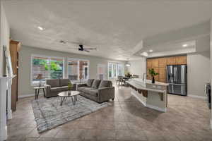 Living room with ceiling fan, recessed lighting, light tile patterned flooring, and a raised ceiling