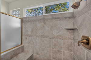 Bathroom featuring healthy amount of natural light and a tile shower