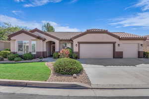 Mediterranean / spanish-style house featuring an attached garage, concrete driveway, stucco siding, and a front lawn