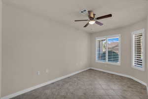Empty room featuring light tile patterned floors and a ceiling fan