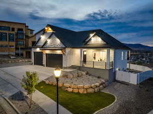 View of front of house featuring an attached garage, stone siding, driveway, a gate, and a balcony