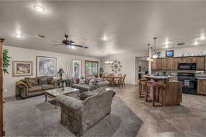 Living room featuring a ceiling fan, vaulted ceiling, and a chandelier