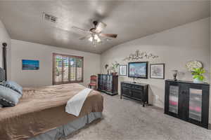 Carpeted bedroom featuring vaulted ceiling, a ceiling fan, and a textured ceiling