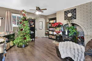 Living area featuring brick wall, wood finished floors, and a ceiling fan