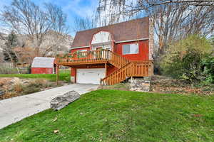Rustic home featuring driveway, a deck, stairway, a front yard, and a garage