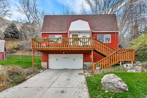 Chalet / cabin featuring a wooden deck, a shingled roof, concrete driveway, and a garage