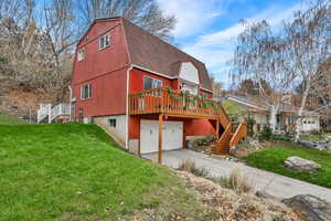 View of home's exterior featuring stairs, a gambrel roof, an attached garage, and a yard