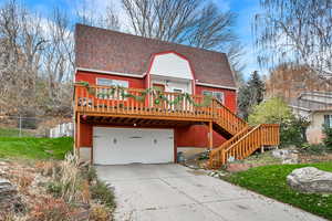 Chalet / cabin featuring a shingled roof, a wooden deck, concrete driveway, and stairway
