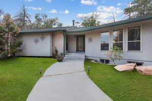 View of front of home featuring stucco siding, a front yard, brick siding, and roof with shingles
