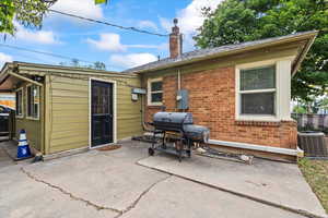 Back of property featuring brick siding, a chimney, and a patio