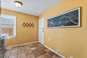Doorway to outside featuring a textured ceiling and stone finish floors