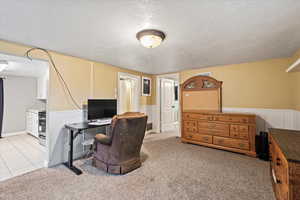 Home office featuring a textured ceiling, light colored carpet, and light tile patterned floors