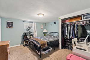 Bedroom featuring a textured ceiling, light colored carpet, and a closet
