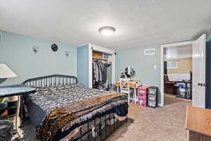 Carpeted bedroom with a textured ceiling and a closet