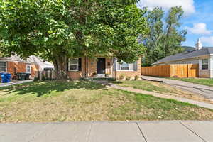 View of property hidden behind natural elements featuring brick siding