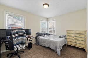 Bedroom with dark carpet and an office area