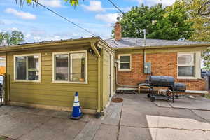 View of side of home with brick siding, a patio, and a chimney