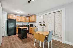 Kitchen featuring black appliances, dark wood-type flooring, decorative marble backsplash, a kitchen island, and granite countertops