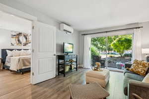 Living room featuring wood finished floors and a wall unit AC