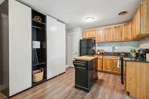 Kitchen featuring light wood-style flooring, marble backsplash, black appliances, and butcher block countertops