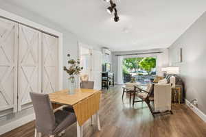 Dining room featuring wood-finished floors, track lighting, and a wall-mounted mini split.