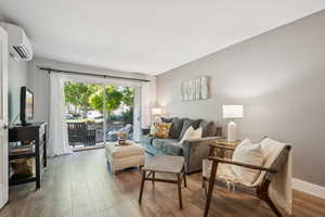 Living area with wood finished floors and an AC wall unit