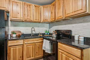 Kitchen with black appliances, marble backsplash, and granite counters