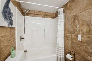 Bathroom with shower / tub combo with curtain and tile walls