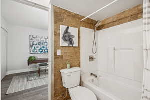 Bathroom with shower / bath combo with shower curtain, tile walls, and wood finished floors