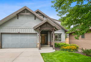 View of front of home with board and batten siding, driveway, a front lawn, and a garage