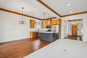 Kitchen with a chandelier, decorative light fixtures, dark wood-style flooring, stainless steel appliances, and recessed lighting