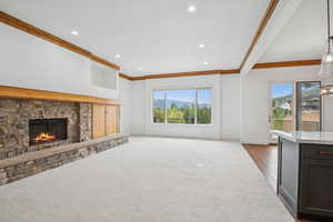 Unfurnished living room featuring a stone fireplace, healthy amount of natural light, ornamental molding, recessed lighting, and dark carpet