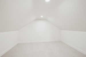 Additional living space with light colored carpet, vaulted ceiling, and recessed lighting