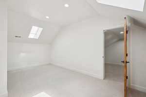 Bonus room featuring a skylight, vaulted ceiling, light colored carpet, and recessed lighting