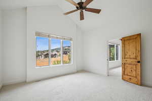 Carpeted empty room with high vaulted ceiling and ceiling fan