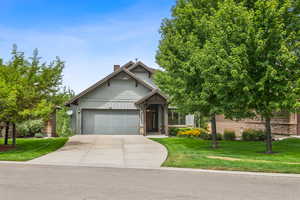 Craftsman inspired home featuring stone siding, a front yard, concrete driveway, and board and batten siding
