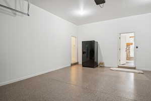 Garage featuring black refrigerator with ice dispenser and a garage door opener