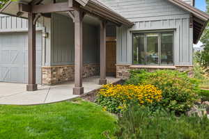 Entrance to property with board and batten siding, stone siding, a porch, and an attached garage