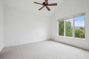 Carpeted spare room featuring a mountain view, high vaulted ceiling, and a ceiling fan