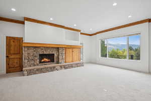 Unfurnished living room featuring a mountain view, a fireplace, carpet floors, crown molding, and recessed lighting